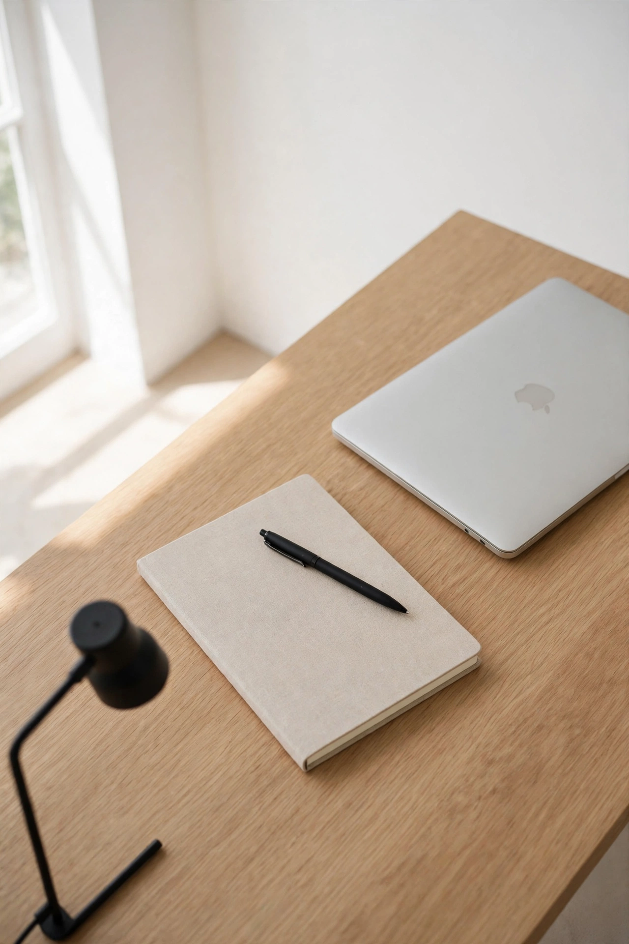 Minimal clear desk with only laptop, lamp and notebook